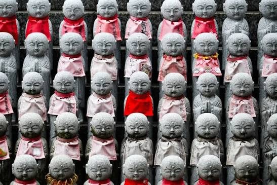 Filas de estatuas de piedra de Jizō con baberos rojos y rosados, en Japón