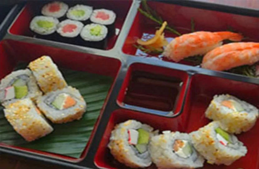 Caja bento con rollos de sushi, nigiri de camarón y salsa de soya