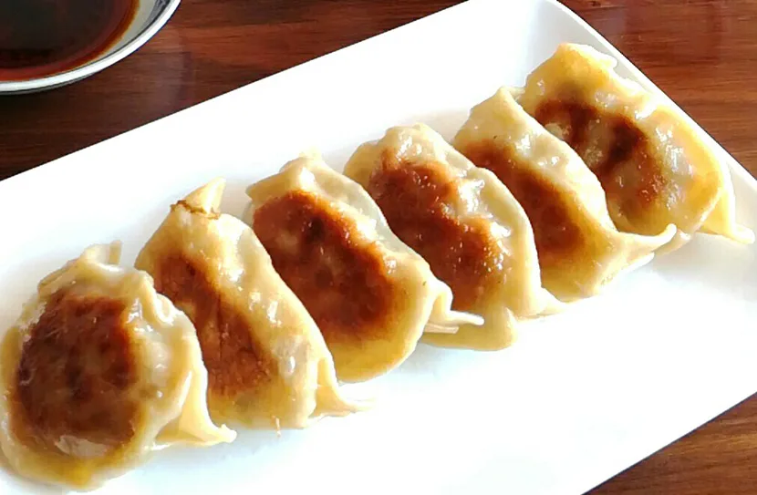 Seis gyoza doradas en un plato blanco